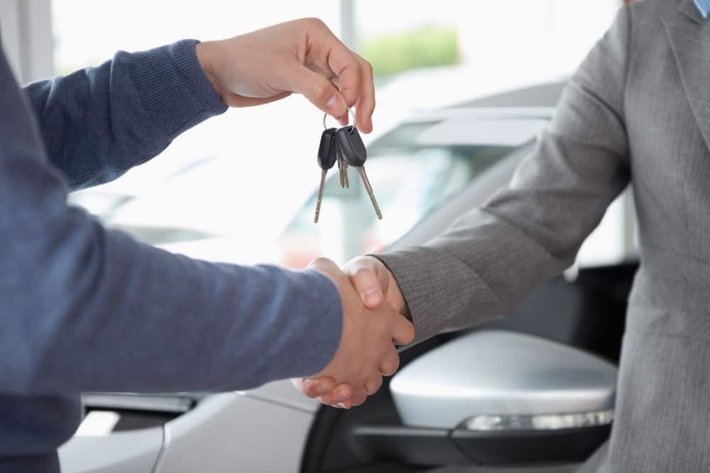 Imagem de homens apertando a mão e trocando a chave do carro