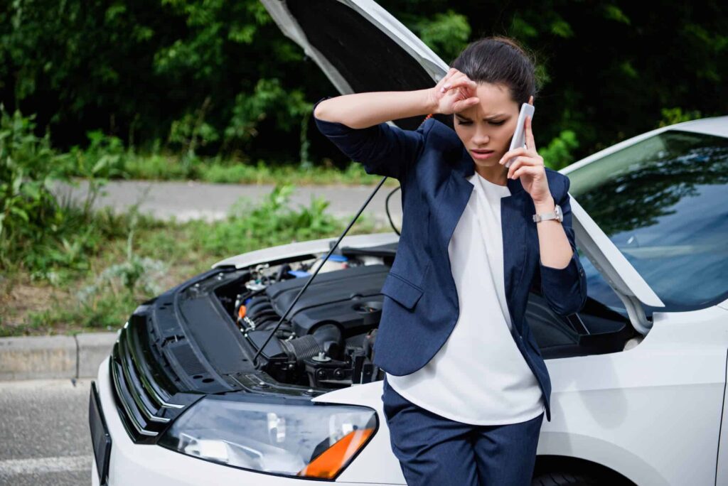 Conheça os problemas mais comuns em veículos e como solucioná-los 7 mulher falando no celular com carro quebrado ao fundo