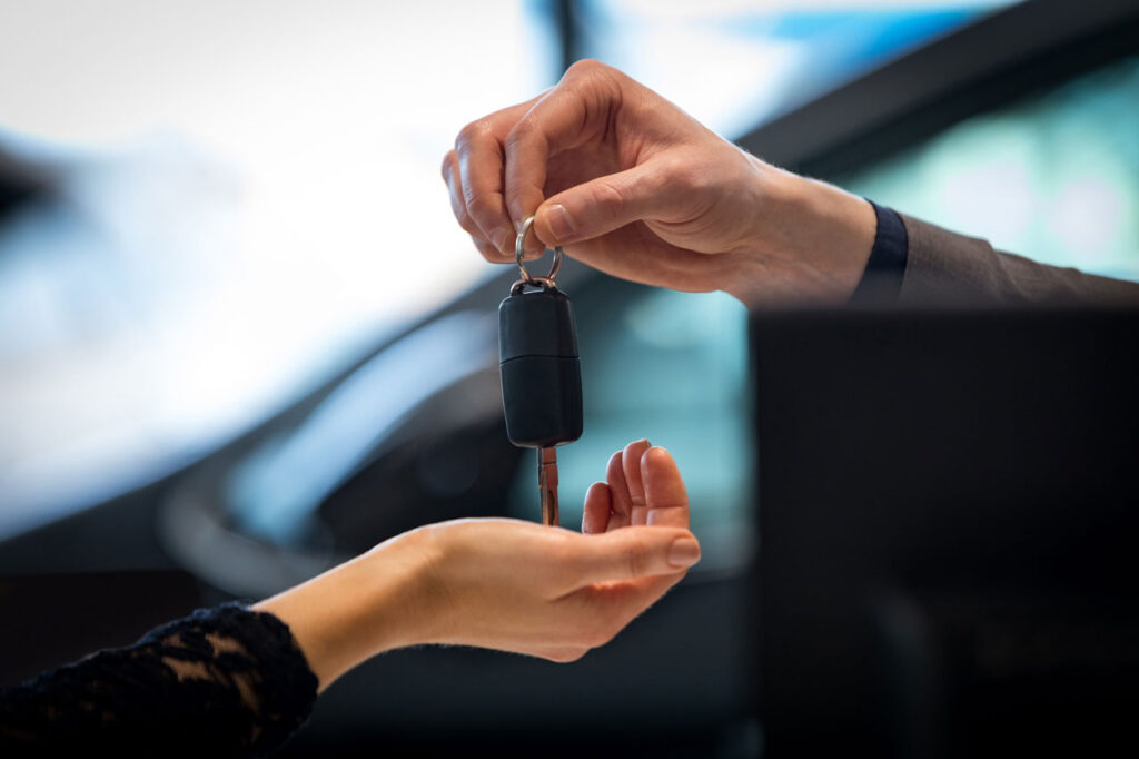 mão entregando uma chave de carro para outra mão - carro alienado