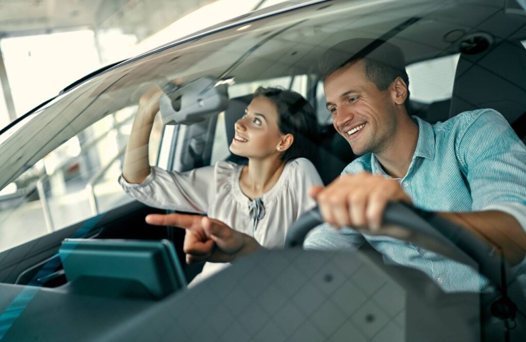 Como pagar menos no imposto de transferência do veículo? 4 como-comprar o carro certo homem e mulher dentro de carro vendo detalhes para comprar - Como pagar menos no imposto de transferência do veículo?