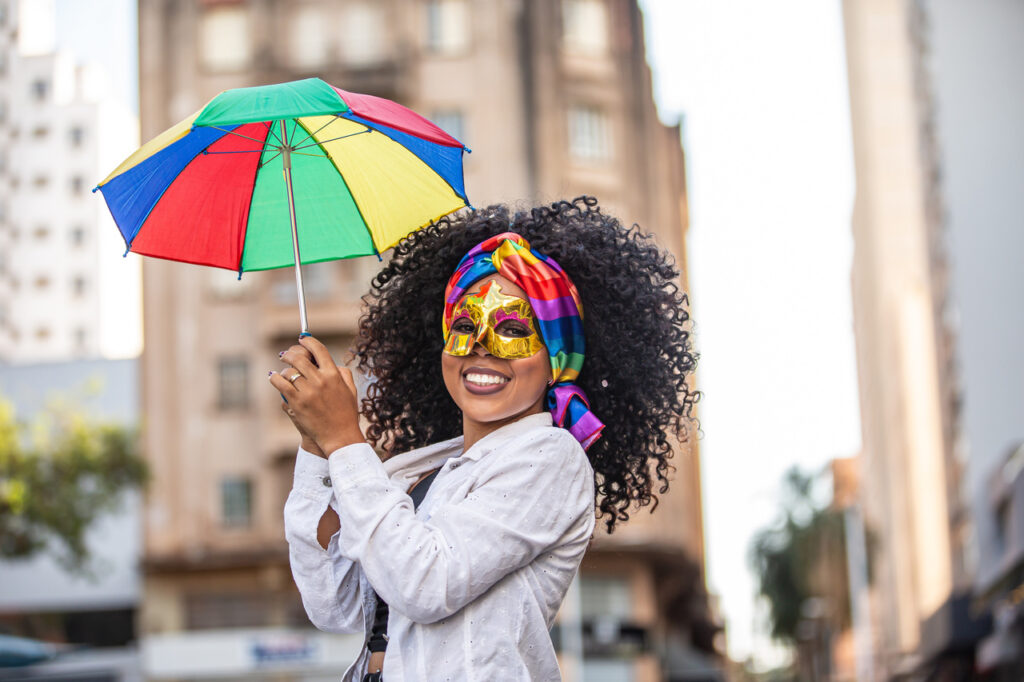 viagem de carnaval - viajar de carro no carnaval - mulher de máscara e guarda-chuva de frevo no carnaval