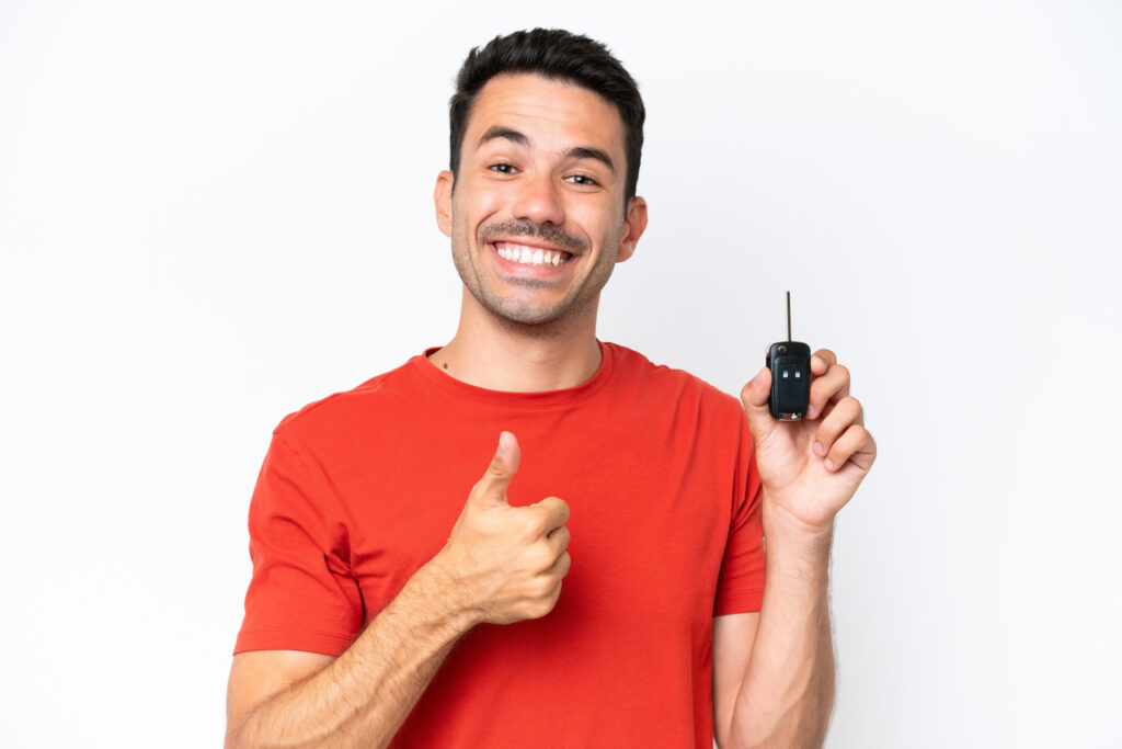 Vender seu carro em Barueri - um homem jovem, sorridente, com camiseta vermelha e segurando uma chave de carro na mão