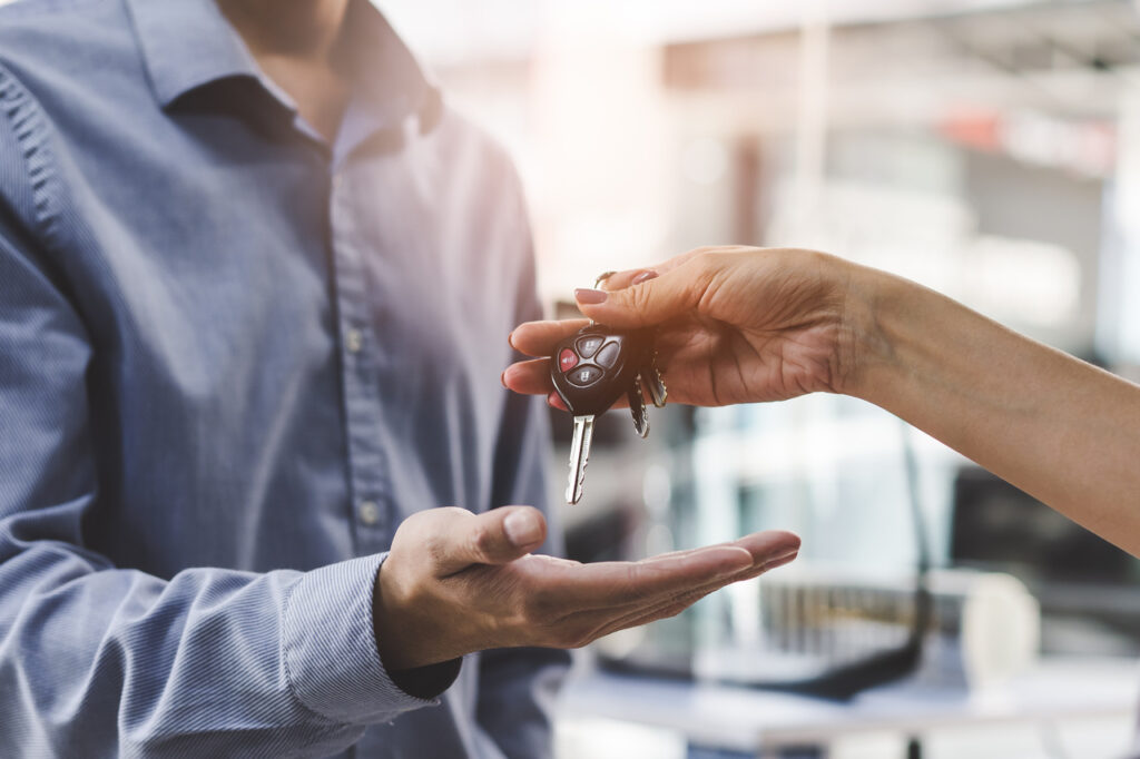 Como vender carro com histórico de leilão 5 vender carro em Duque de Caxias - mão de mulher entregando uma chave de carro na mão de um homem